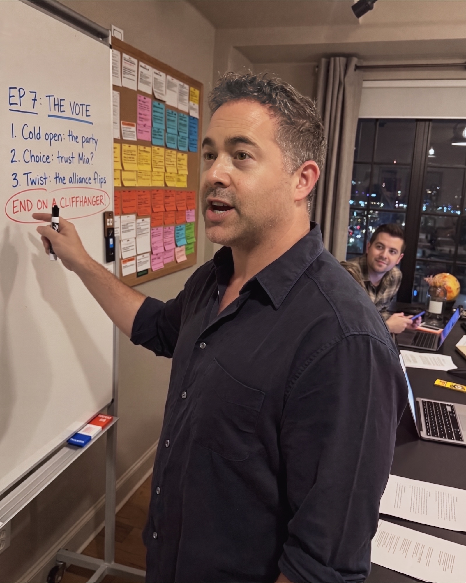 AI render of Arthur as narrative director at a writers’ room whiteboard, marker in hand, pitching an episode’s beats to a writer at the table